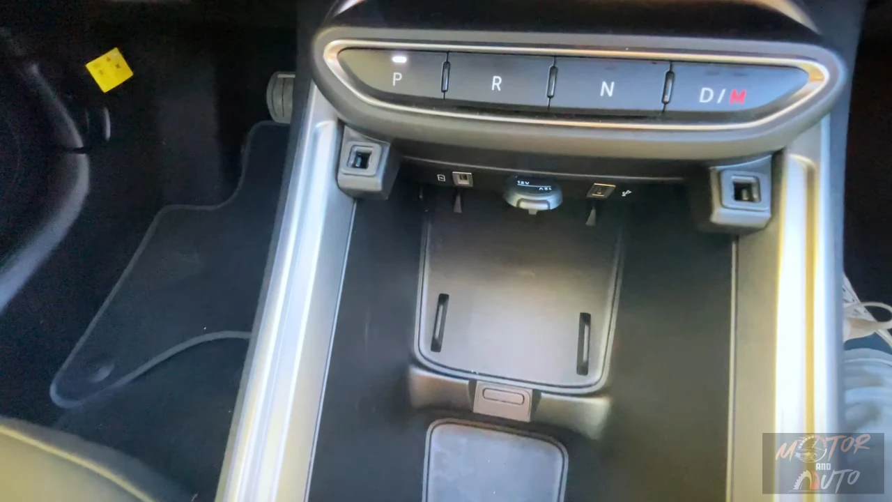 Middenconsole van de 2025 Jeep Avenger met draadloze oplaadpad, meerdere opbergvakken en USB-connectiviteitspoorten voor apparaten.