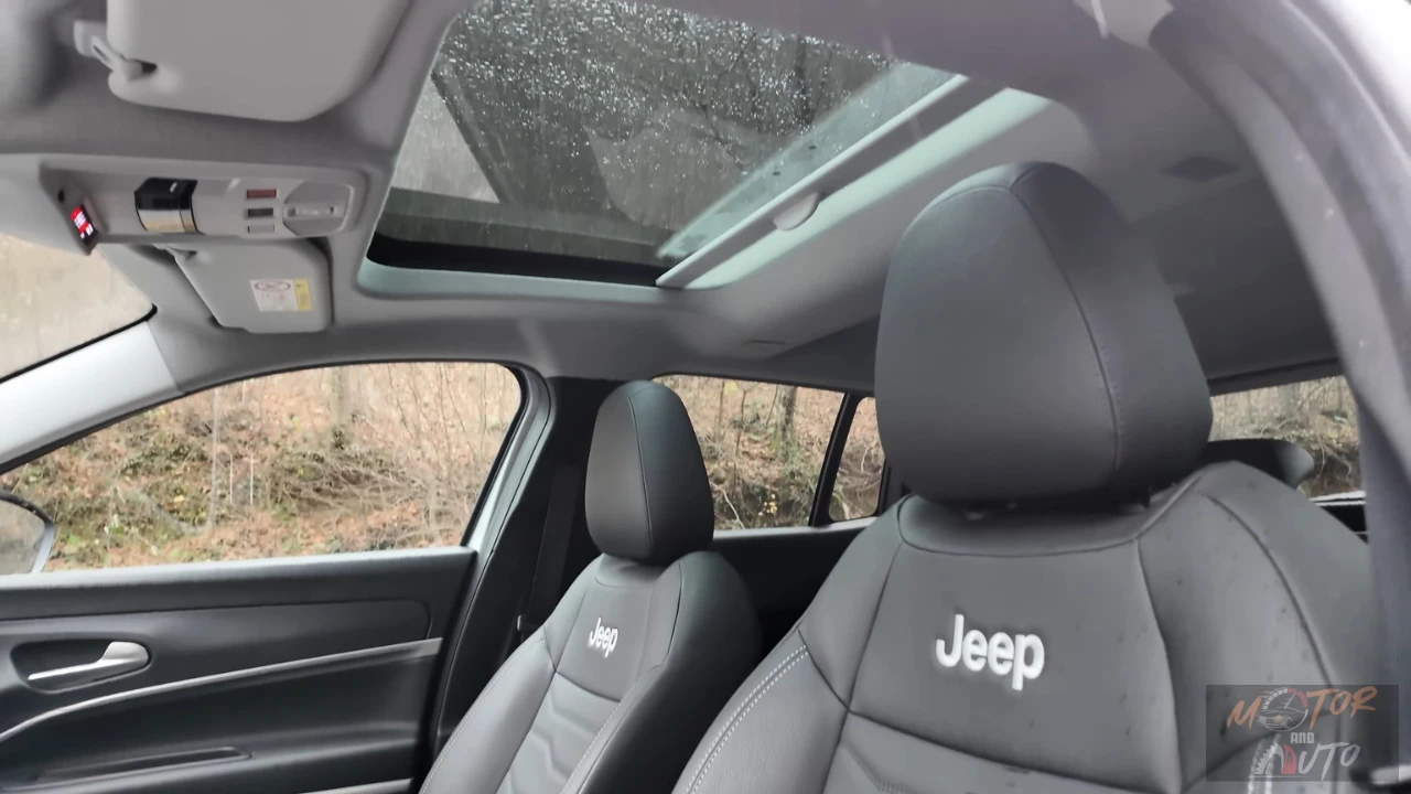 Interieur opname van 2025 Jeep Avenger toont panoramisch schuifdak opening boven voorstoelen met Jeep logo geborduurd hoofdsteunen