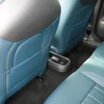 Zicht vanuit achterstoelen van Mini Aceman met beenruimte achter voorstoelen, centrale bekerhouder, USB-oplaadpoorten, en blauwe gewatteerde bekleding