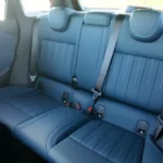 Mini Aceman achterbank in blauw gewatteerd leer met contrasterende stiksels, drie veiligheidsgordels, en ISOFIX kinderzitje bevestigingspunten