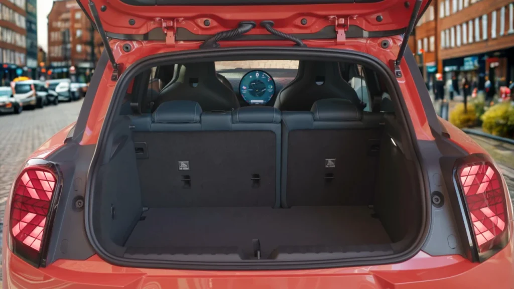 Mini Aceman achterklep open met tapijt bagageruimte met 300L laadruimte, neerklapbare achterstoelen, circulair OLED-display zichtbaar door achterruit, en Union Jack achterlichten