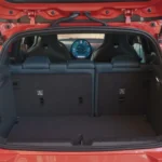 Mini Aceman achterklep open met tapijt bagageruimte met 300L laadruimte, neerklapbare achterstoelen, circulair OLED-display zichtbaar door achterruit, en Union Jack achterlichten