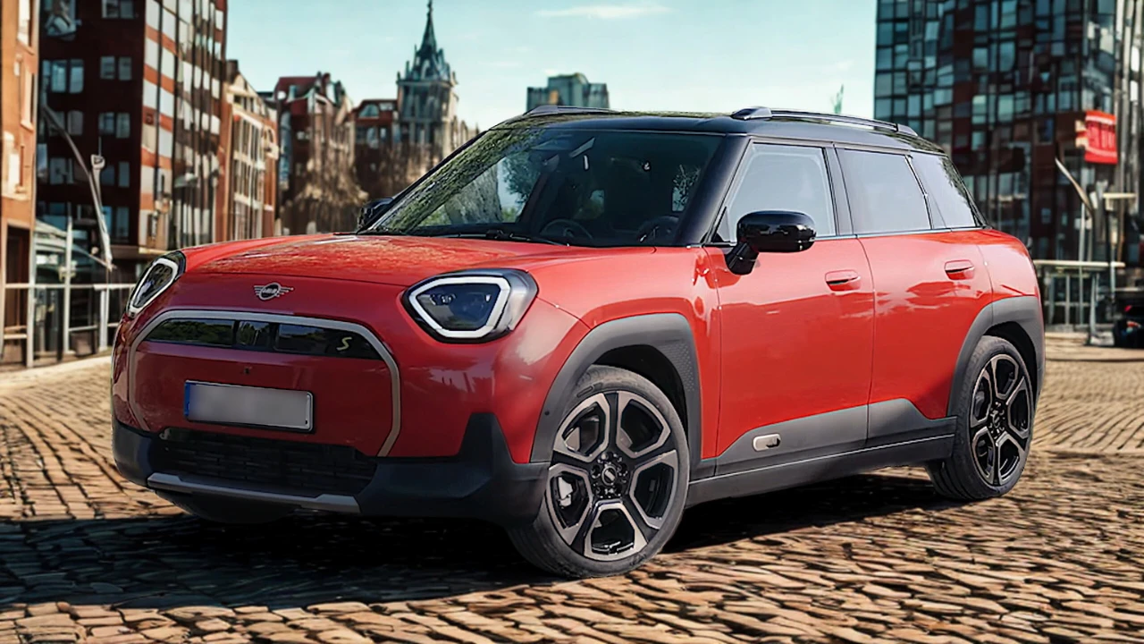 Rode 2025 Mini Aceman elektrische SUV met zwart dak, hoekige LED-koplampen, gesloten EV-grille en tweetone carrosseriebescherming geparkeerd op geplaveide straat met Europese architectuur achtergrond