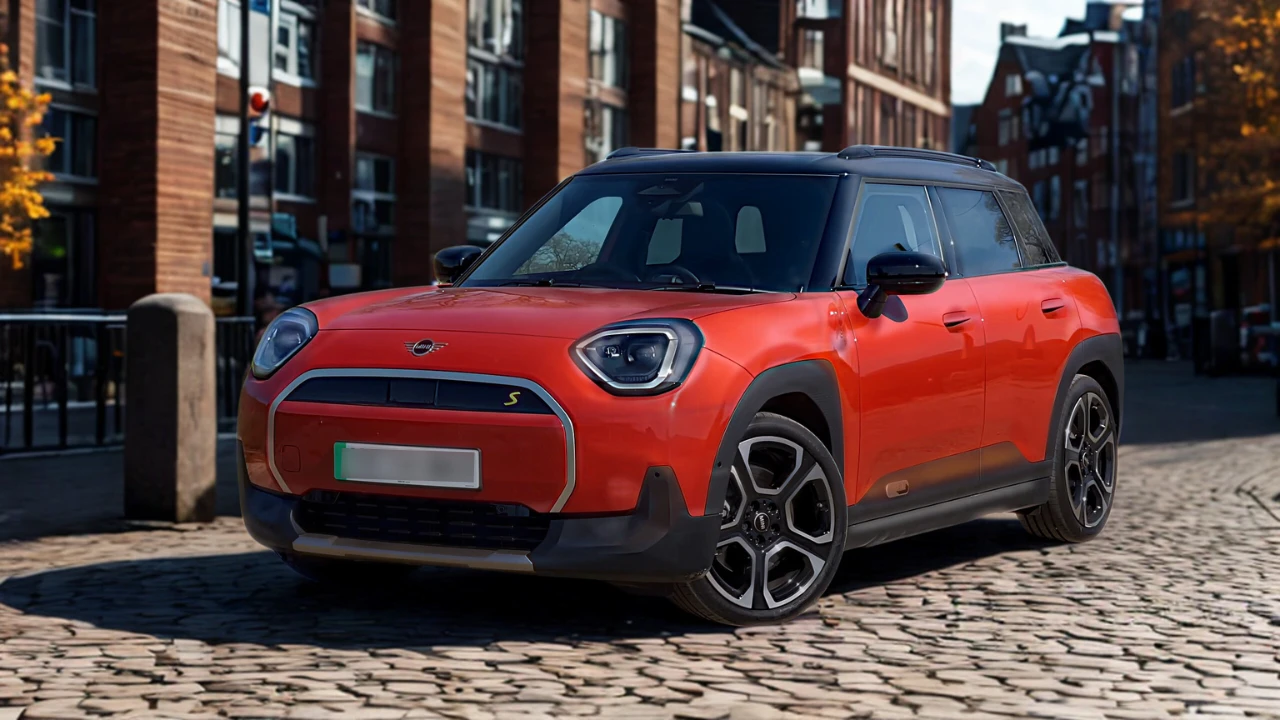 Rode Mini Aceman vanuit voorste driekwarthoek met crossover houding, LED-koplampen, gesloten EV-grille, carrosseriebescherming en moderne lichtmetalen velgen op stadsstraat met eigentijdse gebouwen