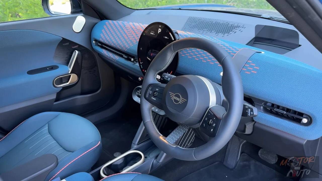 2025 Mini Aceman interieur met blauw gerecycled gebreid stofdashboard, circulair touchscreen-display, stuurwiel met stofband detail, en blauwe bekleding met oranje biezen