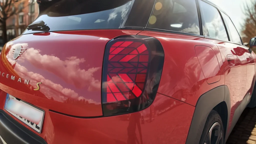 Gedetailleerd zicht van Mini Aceman achterlicht met verlicht Union Jack geometrisch LED-patroon in rode behuizing met ACEMAN badge letters en gele S elektrische aanduiding