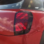 Gedetailleerd zicht van Mini Aceman achterlicht met verlicht Union Jack geometrisch LED-patroon in rode behuizing met ACEMAN badge letters en gele S elektrische aanduiding