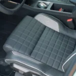 Close-up van de bestuurdersstoel van de 2025 Renault 4 E-Tech Electric met doorgestikt grijs kunstleder met stoffen middensectie en contrasterende stiksels