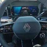 Close-up van het met leder beklede multifunctionele stuurwiel van de 2025 Renault 4 E-Tech Electric met geïntegreerde knoppen voor cruise control, media en rijhulpsystemen