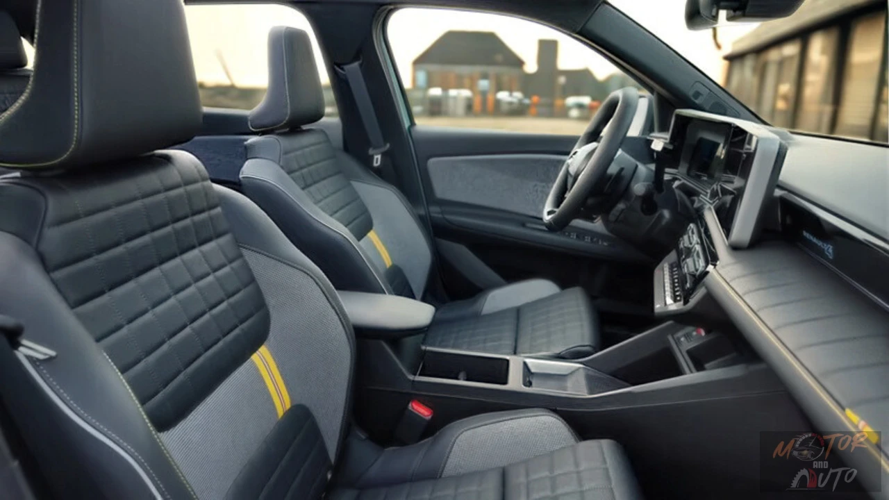 Interieurzicht van de voorstoelen van de 2025 Renault 4 E-Tech Electric met doorgestikt patroon, stoffen bekleding met gele accentnaden en opbergruimte in de middenconsole