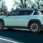 Zijaanzicht van de lichtblauwe 2025 Renault 4 E-Tech Electric met zijn kenmerkende crossover-proporties en drie decoratieve lijnen op de portieren