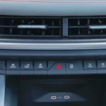 Close-up van 2025 Škoda Enyaq middenconsole met rij bedieningsknoppen inclusief Assist, Mode, Park, waarschuwingslichten en andere voertuigfunctie knoppen