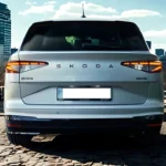 Compleet achteraanzicht van 2025 Škoda Enyaq elektrische SUV in wit met volledige breedte achterlichten, ŠKODA badge en kenteken gebied op kinderkopjes straat