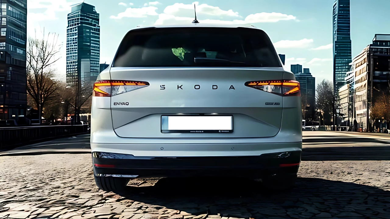 Compleet achteraanzicht van 2025 Škoda Enyaq elektrische SUV in wit met volledige breedte achterlichten, ŠKODA badge en kenteken gebied op kinderkopjes straat
