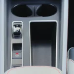 2025 Škoda Enyaq middenconsole met versnellingskiezer met R/N/D/B markeringen, elektronische parkeerrem knop en dubbele bekerhouders in grijze interieur afwerking