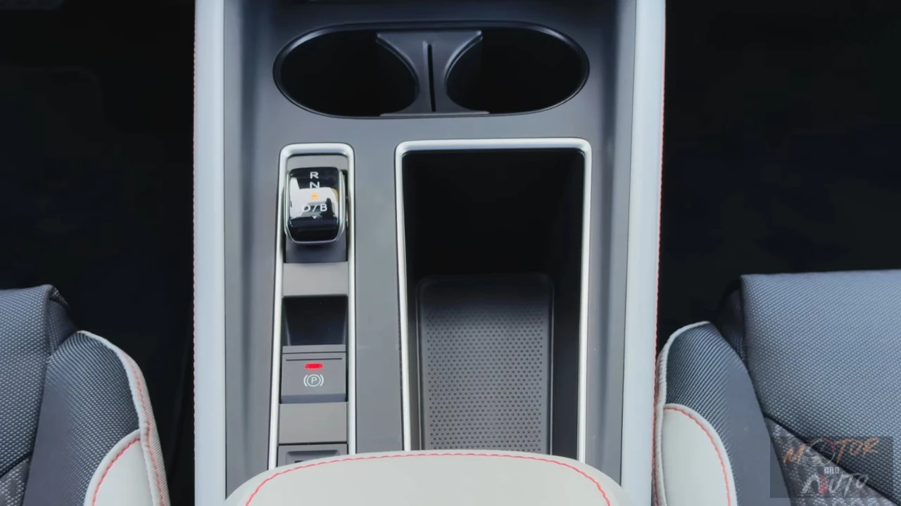 2025 Škoda Enyaq middenconsole met versnellingskiezer met R/N/D/B markeringen, elektronische parkeerrem knop en dubbele bekerhouders in grijze interieur afwerking