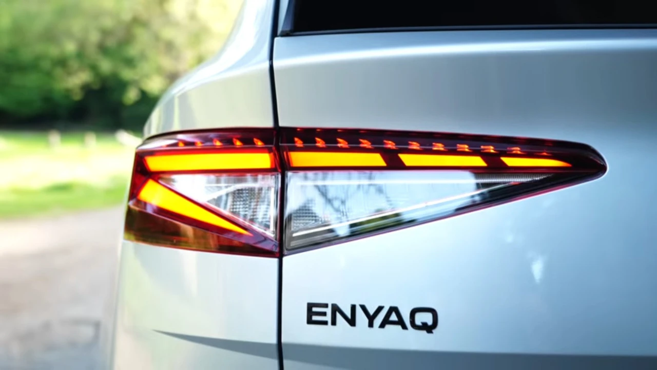 Gedetailleerd beeld van 2025 Škoda Enyaq LED achterlicht met dynamische oranje richtingaanwijzers en ENYAQ letters op witte SUV carrosserie
