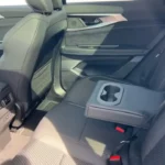Achter zitgebied van de 2025 Renault Austral met middenconsole met bekerhouders, neerklapbare armsteun en comfortabele zitconfiguratie.