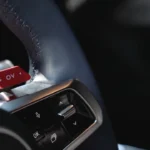 Close-up van de Alpine A390's kenmerkende rode 'OV' overtake knop op het stuurwiel, die directe toegang biedt tot maximaal vermogen voor inhaalmanoeuvres.
