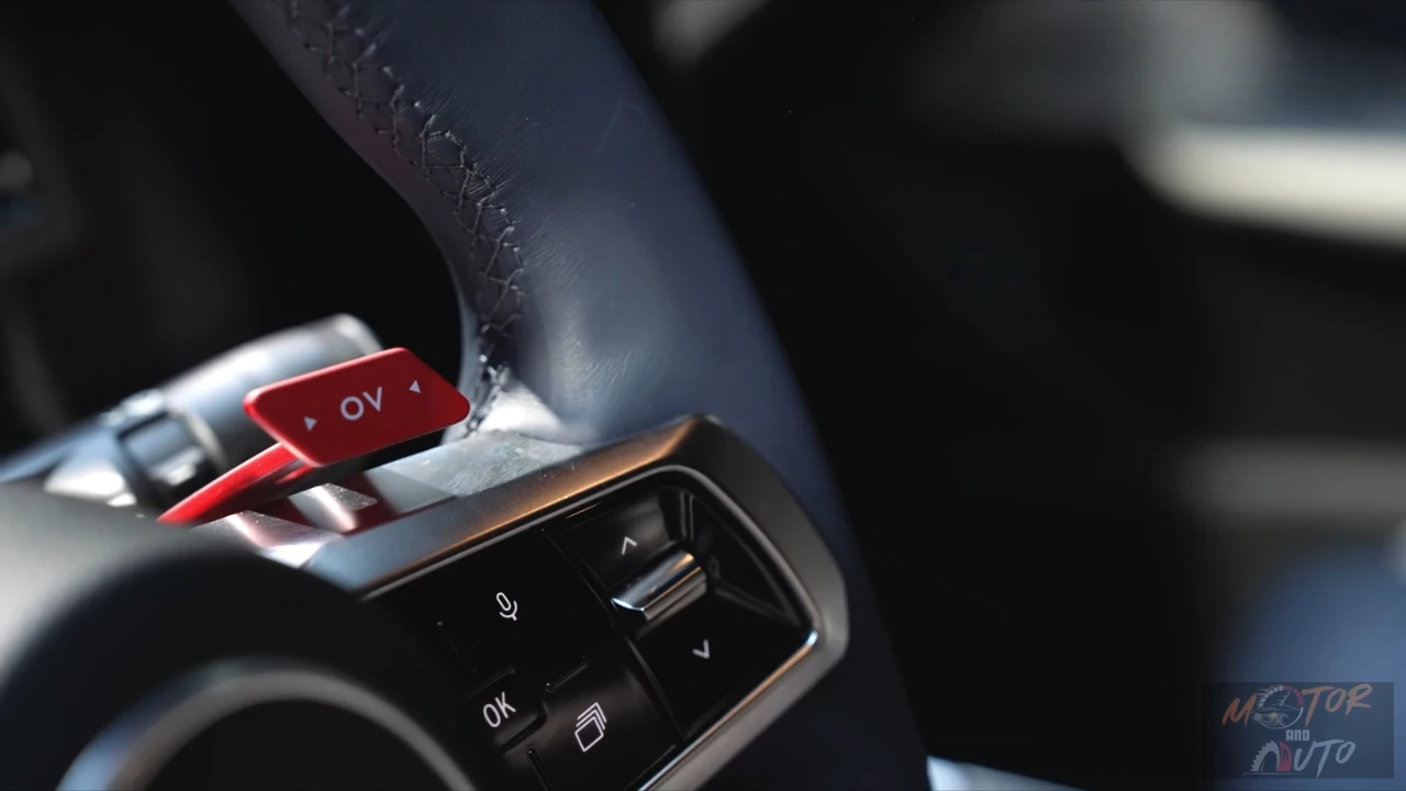 Close-up van de Alpine A390's kenmerkende rode 'OV' overtake knop op het stuurwiel, die directe toegang biedt tot maximaal vermogen voor inhaalmanoeuvres.