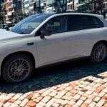 Zijprofiel zicht van 2025 Leapmotor C10 REEV in Pearl White kleur met volledige voertuiglengte, ingebouwde deurgrepen, zwarte dakrails, wielkasten ontwerp en moderne SUV-silhouet tegen stedelijke achtergrond.