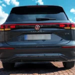 Volledig achteraanzicht van 2025 Volkswagen Tayron met compleet achterontwerp met verlichte elementen tegen Europese stadsarchitectuur