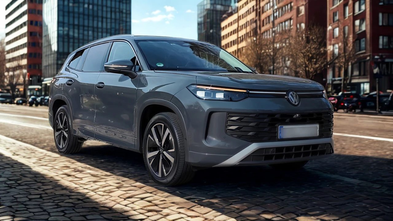 2025 Volkswagen Tayron SUV in grijsmetaalkleurige lak geparkeerd op kinderkopjes met moderne stadsgebouwen op de achtergrond, voor- en zijkant design tonend