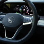 Close-up van 2025 Volkswagen Tayron stuurwiel met leren afwerking, VW-logo en fysieke bedieningsknoppen