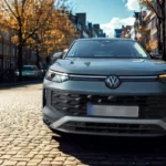 Vooraanzicht van 2025 Volkswagen Tayron met verlichte LED-lichtbalk, matrix-koplampen en VW-logo op Europese kinderkopjes straat