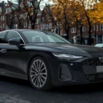 Driekwart vooraanzicht van 2026 Audi A6 sedan op kinderkopjes met totale proporties, meerspaaks lichtmetalen velgen en slanke sedan-profiel
