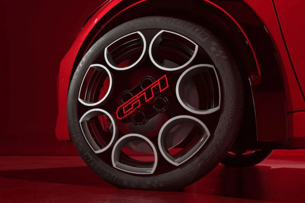 Detail aanzicht van 2026 Peugeot e-208 GTi wiel met 18-inch geperforeerd ontwerp met rood GTi logo in centrum, geïnspireerd door klassieke 205 GTi peperpot wielen