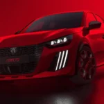Driekwart vooraanzicht van 2026 Peugeot e-208 GTi in helderrood met verlaagde ophanging, brede wielkasten, GTi wielen, en sportief voorkant ontwerp