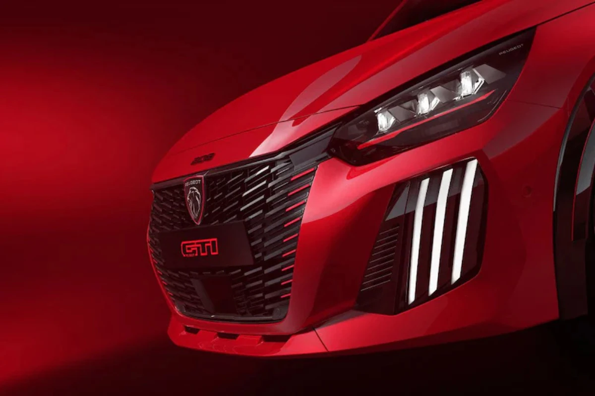 Vooraanzicht detail van 2026 Peugeot e-208 GTi met zwarte honingraat grill met rode GTi badge, LED koplamp cluster, en sportieve voorbumper met luchtinlaten