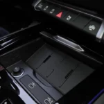 De middenconsole van de 2025 Audi Q3 met open schuifklep, die de draadloze oplaadzone en extra opslagruimte voor persoonlijke items toont.
