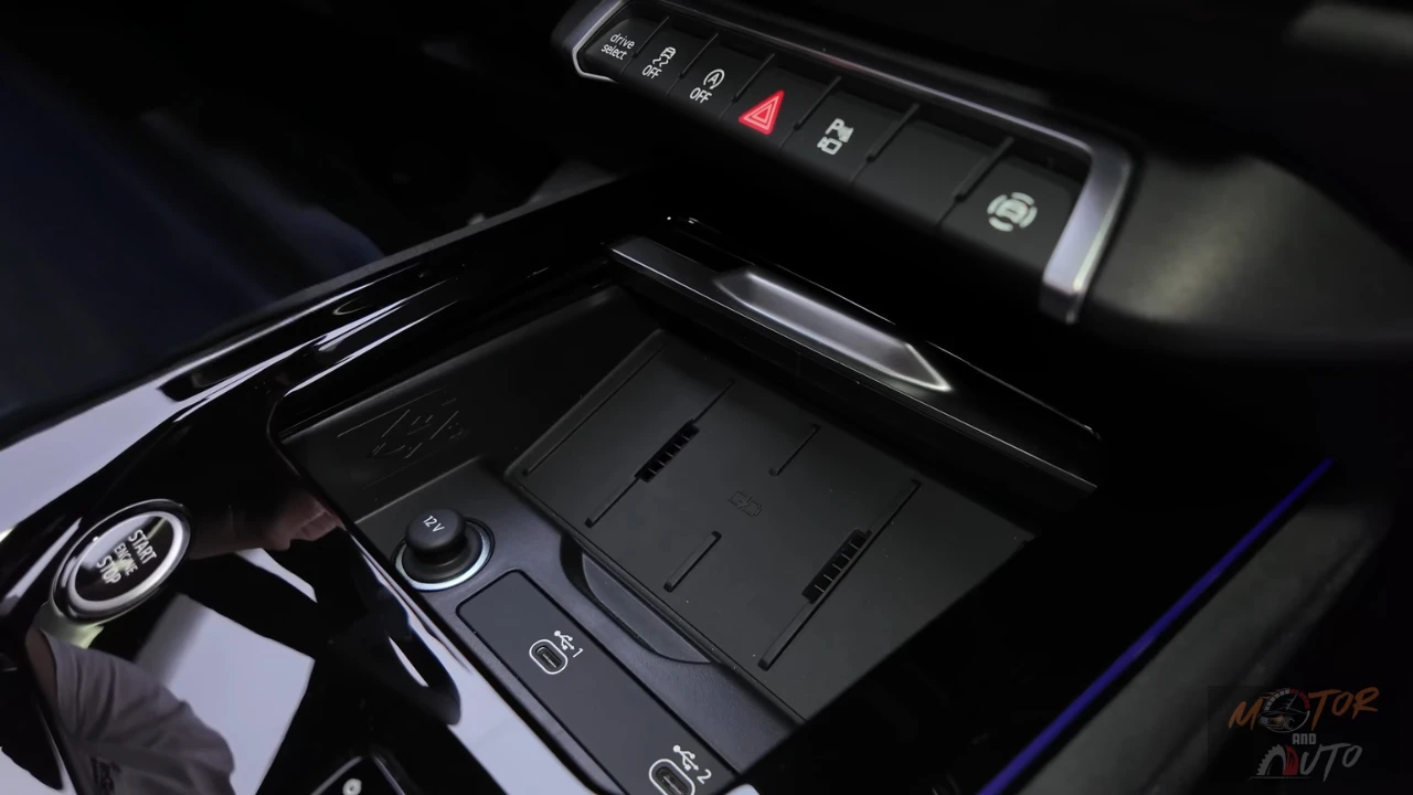 De middenconsole van de 2025 Audi Q3 met open schuifklep, die de draadloze oplaadzone en extra opslagruimte voor persoonlijke items toont.