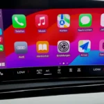 Centrale touchscreen van 2026 Audi A6 met Apple CarPlay interface, app-iconen, klimaatcontrolepaneel en geïntegreerde smartphone-connectiviteitsfuncties