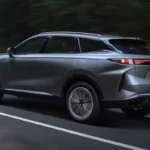Achterkant driekwart dynamisch zicht van donkergrijze Omoda 09 in beweging op snelweg met LED achterlicht ontwerp, achterspoiler, dubbele uitlaat uitgangen en gestroomlijnde aerodynamische profiel tijdens het rijden