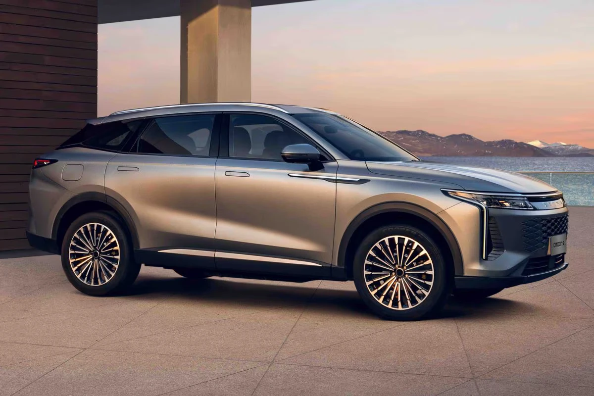 Zijprofiel van champagne gouden Omoda 09 hybride SUV met 20-inch lichtmetalen velgen, moderne LED verlichting en gestroomlijnde coupé-achtige daklijn tegen zonsondergang achtergrond