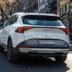 2026 Kia Sportage witte SUV achteraanzicht met LED achterlichten met rode verlichting, Sportage letters, Kia logo, kenteken gebied en uitlaatmondstukken op straat met herfstbomen en stedelijke gebouwen