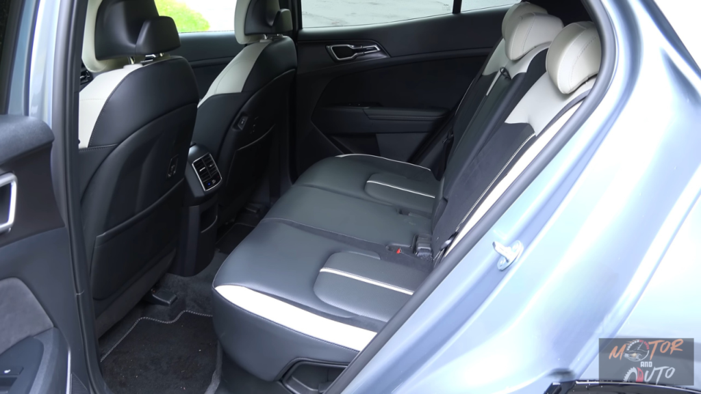 2026 Kia Sportage achterpassagiers gebied met ruime beenruimte, tweekleurige stoelbekleding, achter luchtroosters en raam uitzicht dat interieur ruimte toont