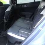 2026 Kia Sportage achterpassagiers gebied met ruime beenruimte, tweekleurige stoelbekleding, achter luchtroosters en raam uitzicht dat interieur ruimte toont