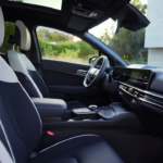 2026 Kia Sportage GT-Line interieur met voorstoelen in wit en zwarte tweekleurige bekleding, panoramadak erboven en premium dashboard materialen