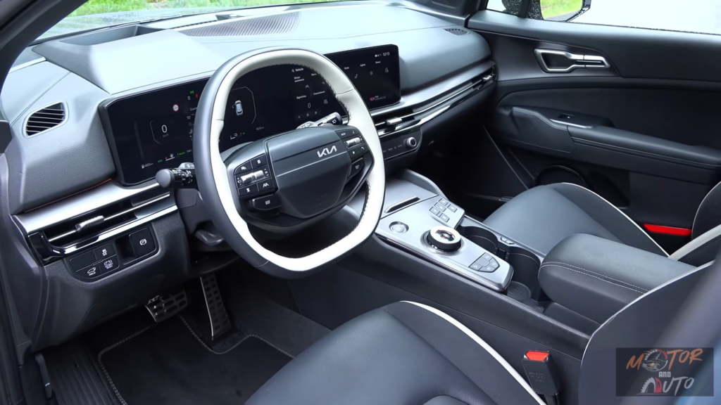 2026 Kia Sportage interieur met nieuw tweespaaks stuurwiel, dubbele 12,3-inch curved displays, middenconsole met roterende versnellingspook en zwarte leren stoelen met witte biezen