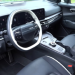 2026 Kia Sportage interieur met nieuw tweespaaks stuurwiel, dubbele 12,3-inch curved displays, middenconsole met roterende versnellingspook en zwarte leren stoelen met witte biezen