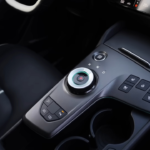 2026 Kia Sportage middenconsole met roterende versnellingspook met blauwe accent verlichting, rijmodus knoppen, stoelverwarming bediening en bekerhouders
