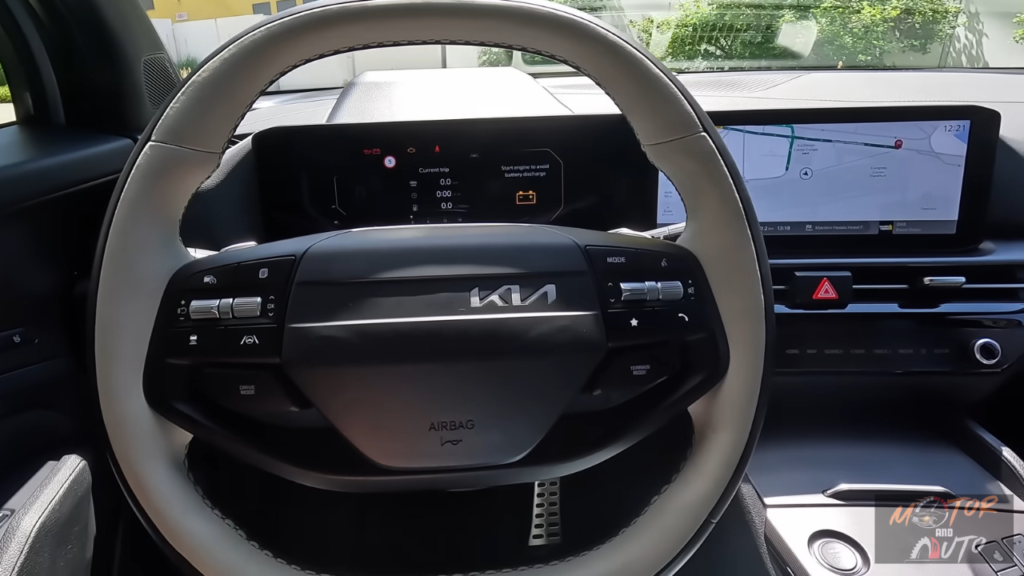 2026 Kia Sportage stuurwiel detail met nieuw tweespaaks design met bedieningsknoppen en digitaal display met hybride batterijstatus en rit informatie