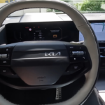 2026 Kia Sportage stuurwiel detail met nieuw tweespaaks design met bedieningsknoppen en digitaal display met hybride batterijstatus en rit informatie