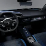 Interieur aanzicht van 2026 Maserati MCPura met zwart Alcantara dashboard, suède-omwikkeld stuurwiel met Maserati logo, blauwe accent stiksels op stoelen, en racing-geïnspireerd cockpit layout