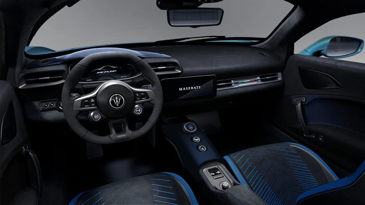 Interieur aanzicht van 2026 Maserati MCPura met zwart Alcantara dashboard, suède-omwikkeld stuurwiel met Maserati logo, blauwe accent stiksels op stoelen, en racing-geïnspireerd cockpit layout