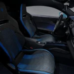 Volledige interieur cabine aanzicht van 2026 Maserati MCPura met racing kuipstoelen met blauwe laser-geëtste patronen, centrale console met transmissie bedieningselementen, carbon fiber accenten, en uitgebreide bestuurder-gerichte cockpit layout